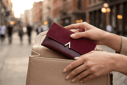 Portefeuille femme long bordeaux Celestia tenu par des mains féminines élégantes — Novaleor
